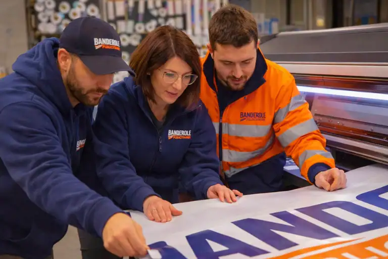 Techniciens réalisant l’impression d’une banderole publicitaire en atelier